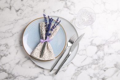 Photo of Cutlery, napkin, plates, glass and preserved lavender flowers on white marble table, flat lay. Space for text