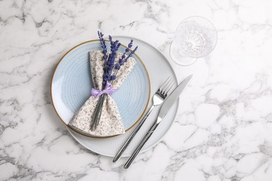 Cutlery, napkin, plates, glass and preserved lavender flowers on white marble table, flat lay. Space for text