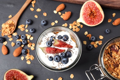 Photo of Tasty homemade granola with yogurt on dark grey table, flat lay. Healthy breakfast