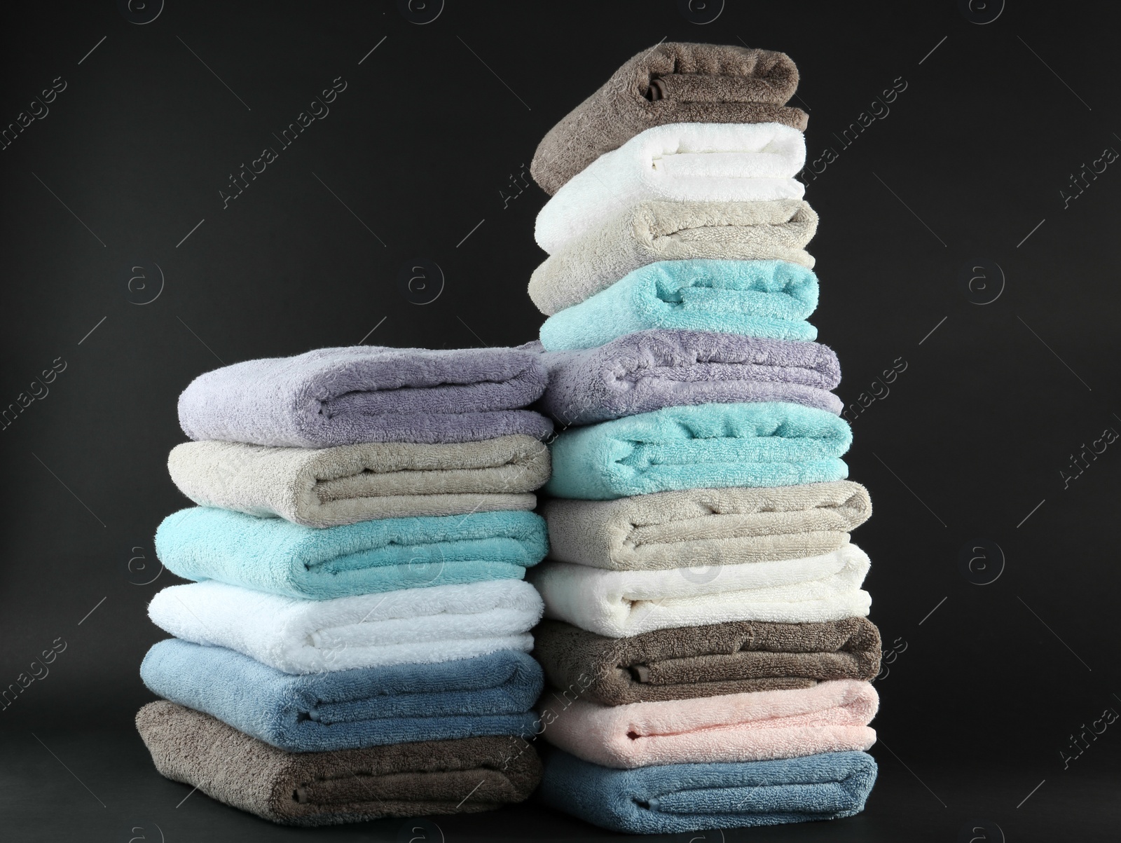 Photo of Different fresh soft terry towels on dark background