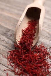 Photo of Aromatic saffron and scoop on wooden table, closeup