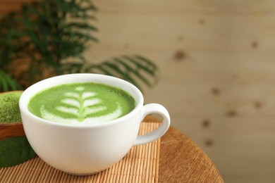 Photo of Delicious matcha latte in cup and powder on wooden coffee table, closeup. Space for text