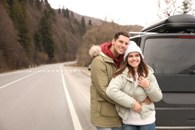 Happy couple near car on road. Winter vacation
