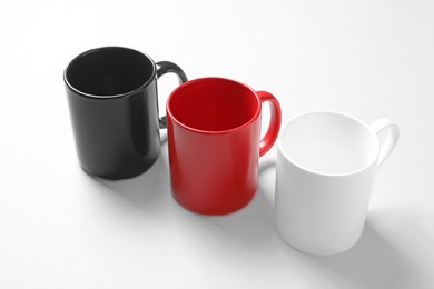 Photo of Three colorful ceramic mugs on light background