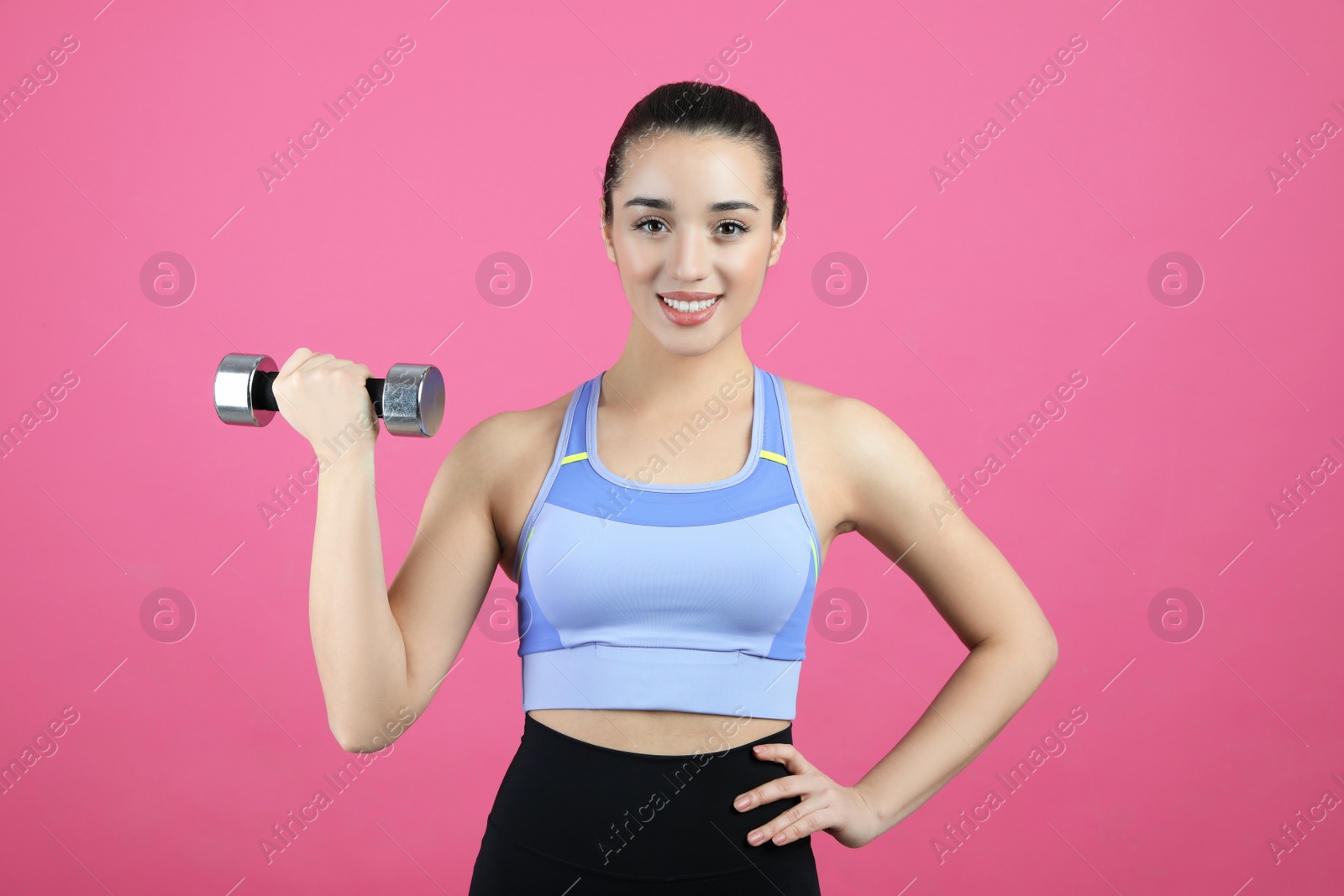 Photo of Woman with dumbbell as girl power symbol on pink background. 8 March concept