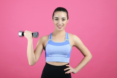 Photo of Woman with dumbbell as girl power symbol on pink background. 8 March concept