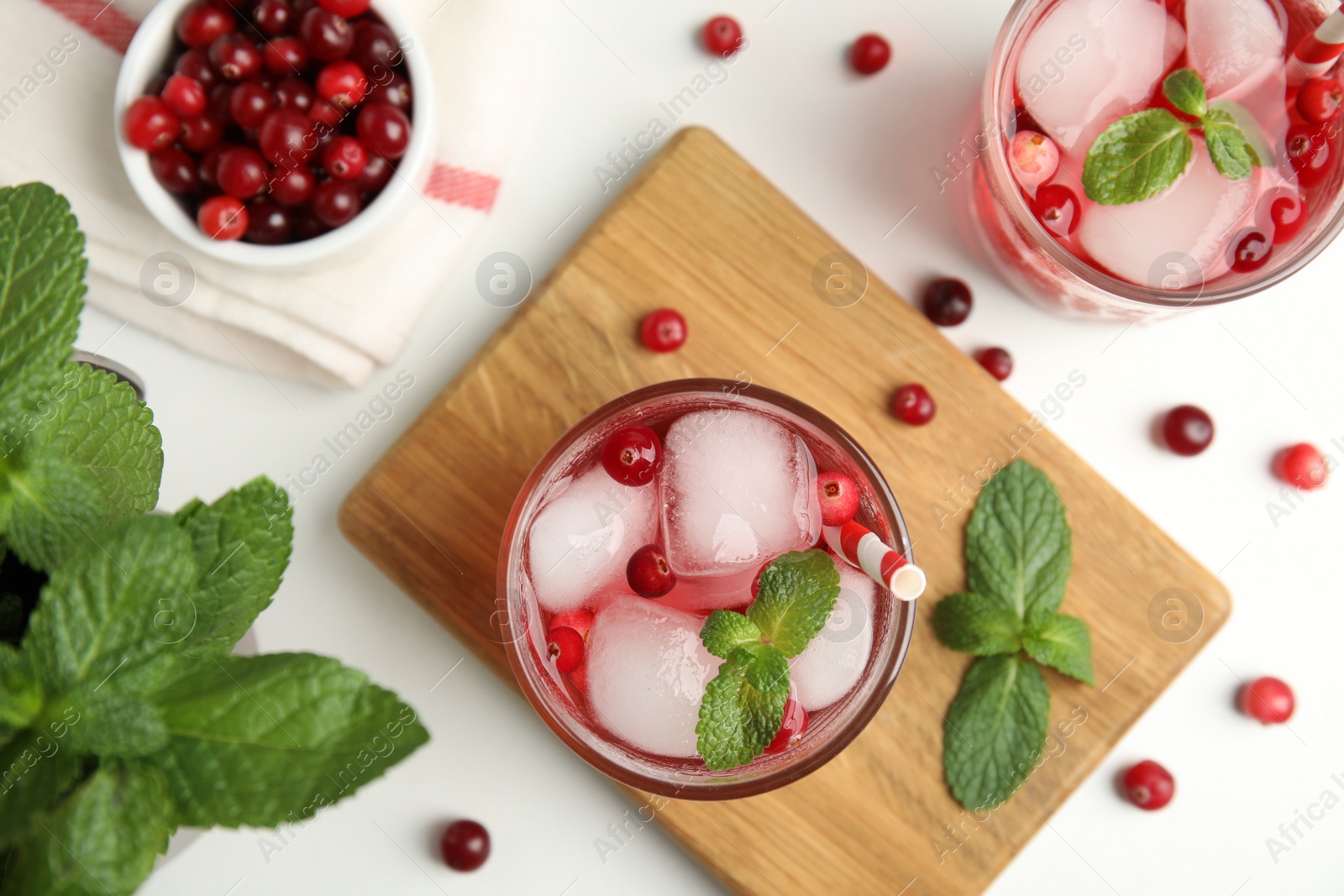 Photo of Tasty refreshing cranberry cocktail with mint on white table, flat lay