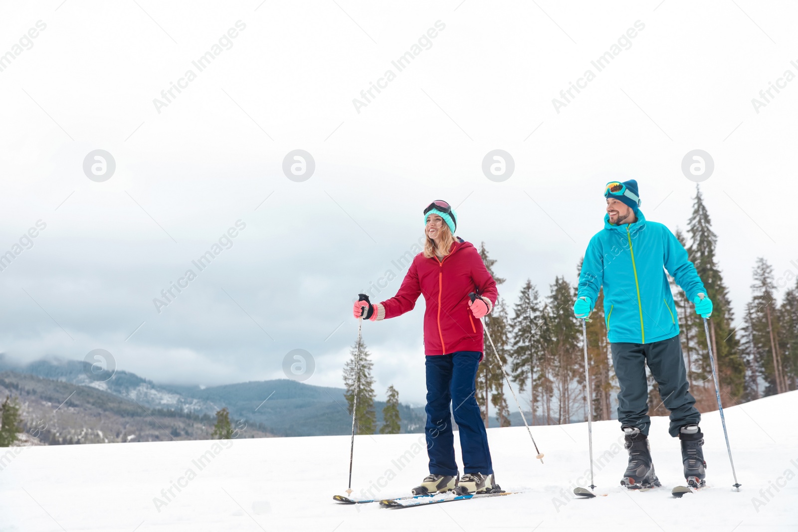 Photo of Couple of skiers on slope at resort, space for text. Winter vacation