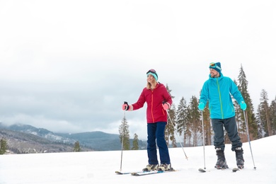 Couple of skiers on slope at resort, space for text. Winter vacation