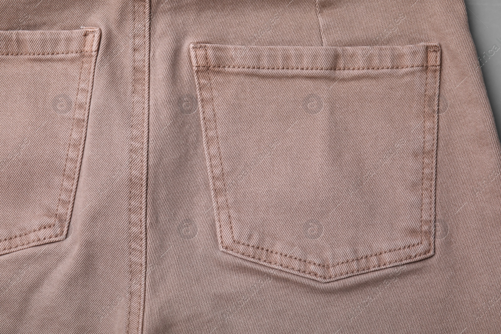 Photo of Beige jeans with pockets on grey background, closeup