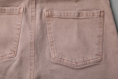 Beige jeans with pockets on grey background, closeup