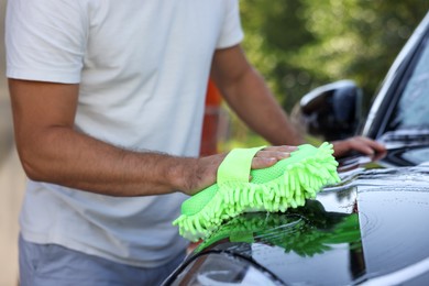 Photo of Man washing car with sponge outdoors, closeup