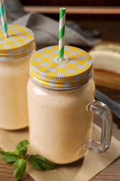 Tasty banana smoothie and mint on wooden table