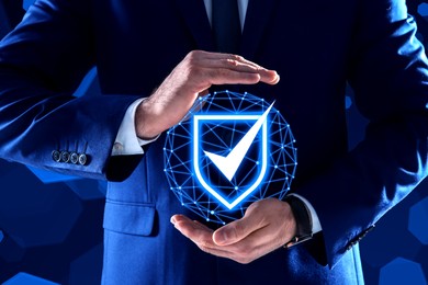 Anti-fraud security system. Man with illustration of checkmark in shield on dark blue background, closeup