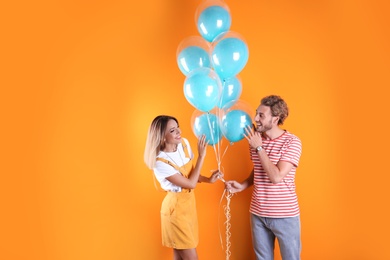 Photo of Young couple with air balloons on color background