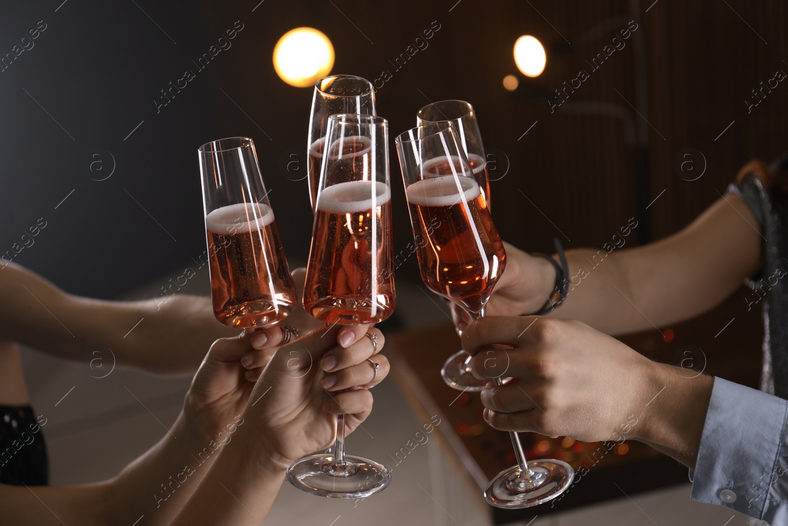 Photo of Friends clinking glasses with champagne on blurred background, closeup