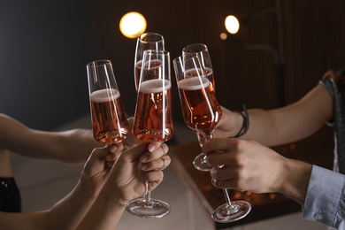 Friends clinking glasses with champagne on blurred background, closeup