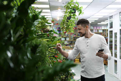 Photo of Male business owner with phone in his flower shop