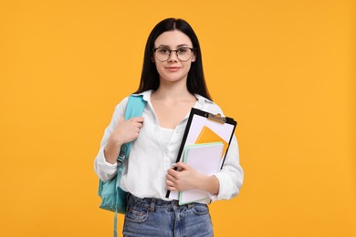 Student with notebooks and clipboard on yellow background