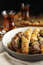 Photo of Delicious sweet baklava in bowl on table, closeup