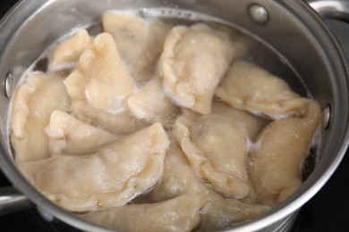 Photo of Boiling delicious dumplings (varenyky) in pot, closeup