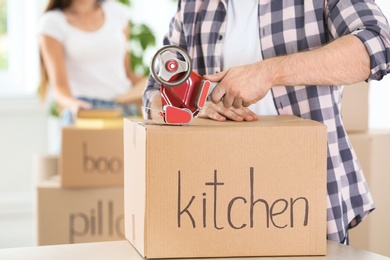 Man packing cardboard box indoors, closeup. Moving day