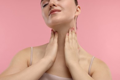 Photo of Woman touching her neck on pink background, closeup