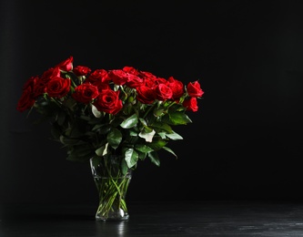 Vase with beautiful red rose flowers on black background