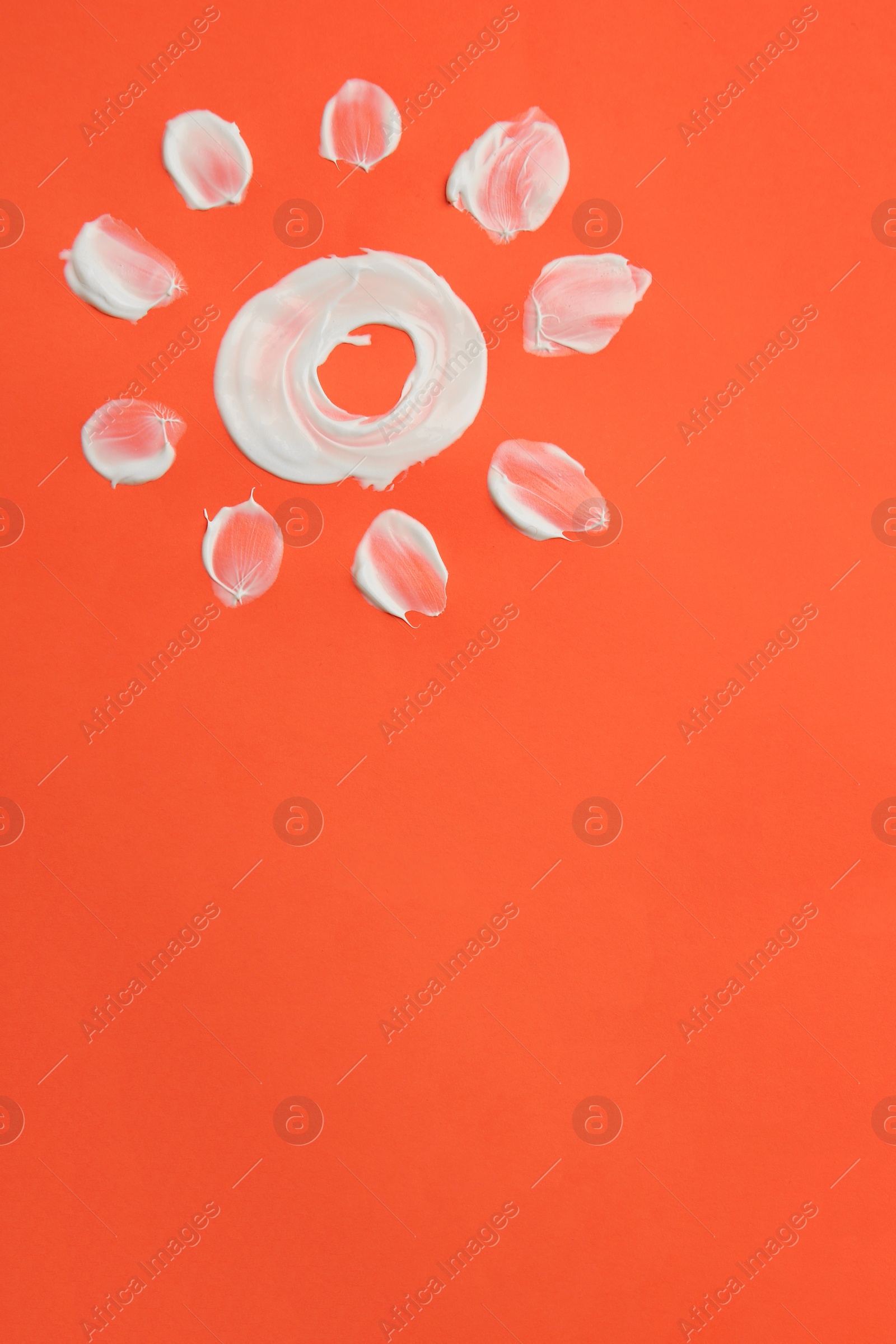 Photo of Sun drawn with sunscreen on coral background, top view and space for text. Skin protection