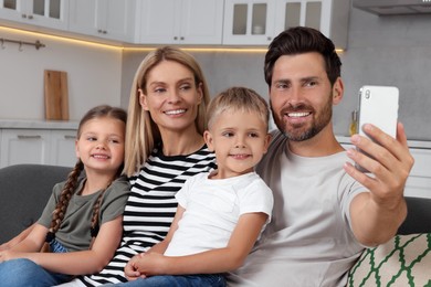 Photo of Happy family taking selfie together on sofa at home