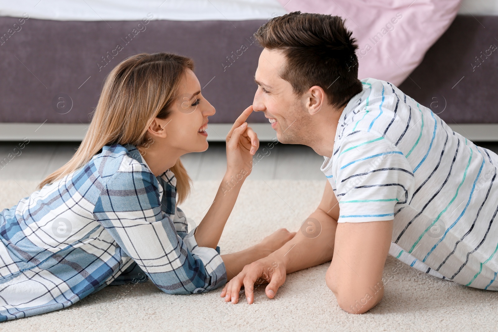 Photo of Lovely young couple lying on cozy carpet at home