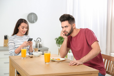 Young woman preferring smartphone over her boyfriend at home