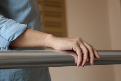 Woman leaning on metal railing indoors, closeup