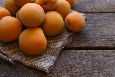 Photo of Delicious ripe apricots with napkin on wooden table, closeup