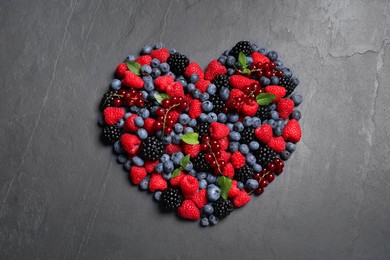 Photo of Heart made of different fresh ripe berries on dark grey table, top view