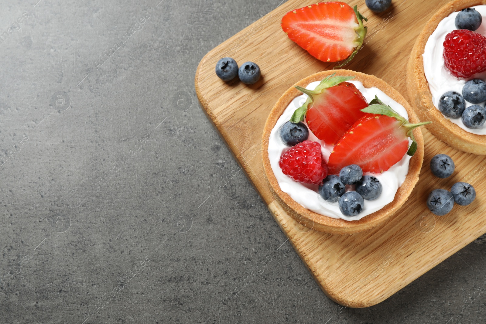 Photo of Delicious sweet pastries with berries on grey table, top view. Space for text