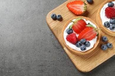 Delicious sweet pastries with berries on grey table, top view. Space for text