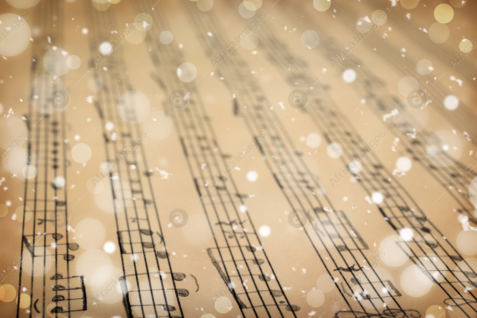 Image of Old sheet with Christmas music notes as background, snowflakes and bokeh effect