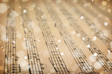 Image of Old sheet with Christmas music notes as background, snowflakes and bokeh effect