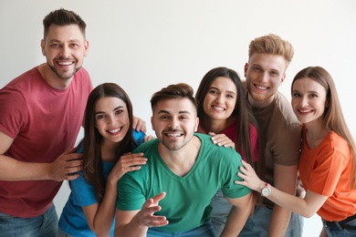 Group of happy people posing near light wall