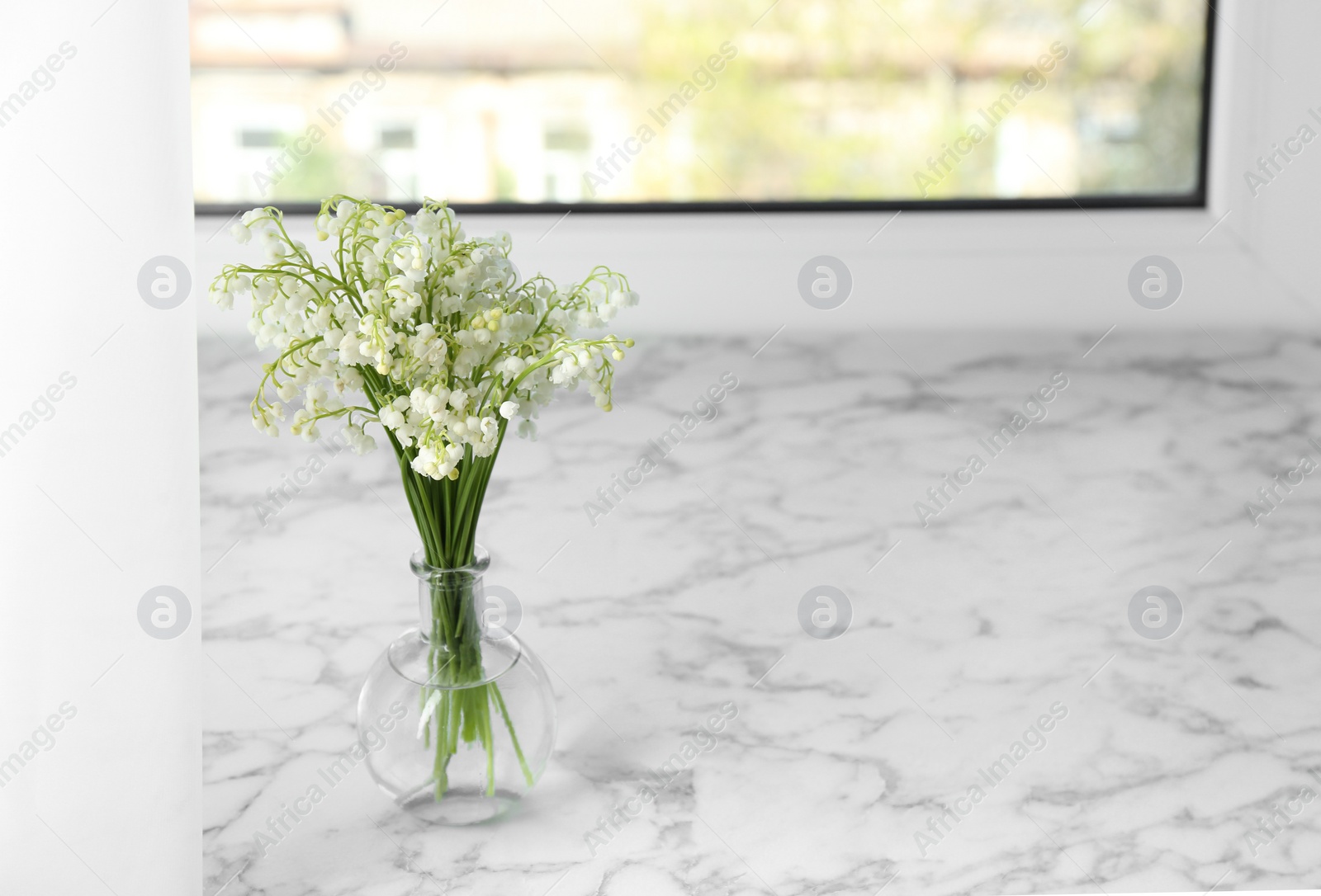 Photo of Beautiful lily of the valley bouquet in vase on windowsill, space for text