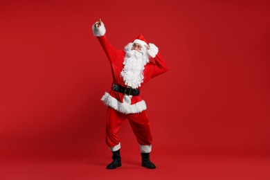 Photo of Merry Christmas. Santa Claus pointing at something on red background