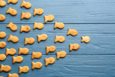 Photo of Delicious goldfish crackers on blue wooden table, flat lay