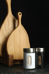 Photo of Salt and pepper shakers and wooden boards on black table