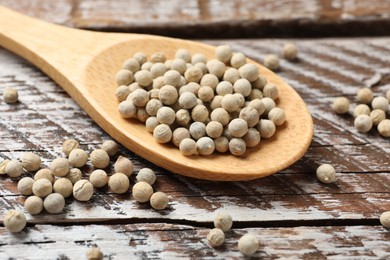 Photo of Aromatic spice. White pepper in spoon on wooden table, closeup