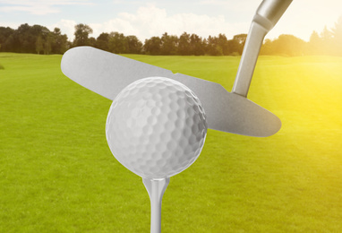 Image of Hitting golf ball with club in park on sunny day