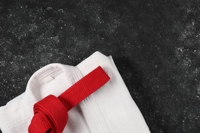 Photo of Red karate belt and white kimono on gray textured background, top view. Space for text