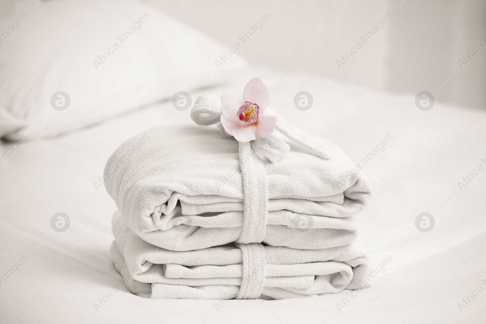Photo of Clean folded bathrobes on bed in room