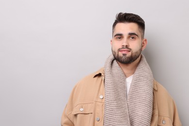 Handsome man in warm scarf on light grey background. Space for text