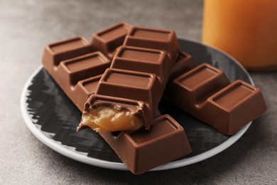 Photo of Plate with tasty chocolate bars on grey table, closeup